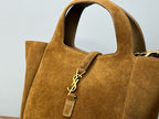 Tan suede tote bag close-up with YSL logo charm and small zip pull tag