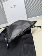Black leather drawstring bag side view with gold-toned logo and strap hardware