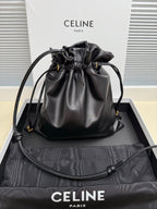 Black leather drawstring bag with gold-toned logo and adjustable shoulder strap