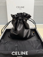 Black leather drawstring bag with ruffled top and gold-toned hardware, shoulder carry