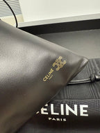 Black leather bag corner with gold-tone logo emblem and pull tab