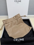 Beige leather pouch with front seam, two handles, and small metal hardware accents