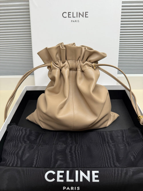 Beige leather drawstring pouch bag with ruched top and braided cord shoulder strap