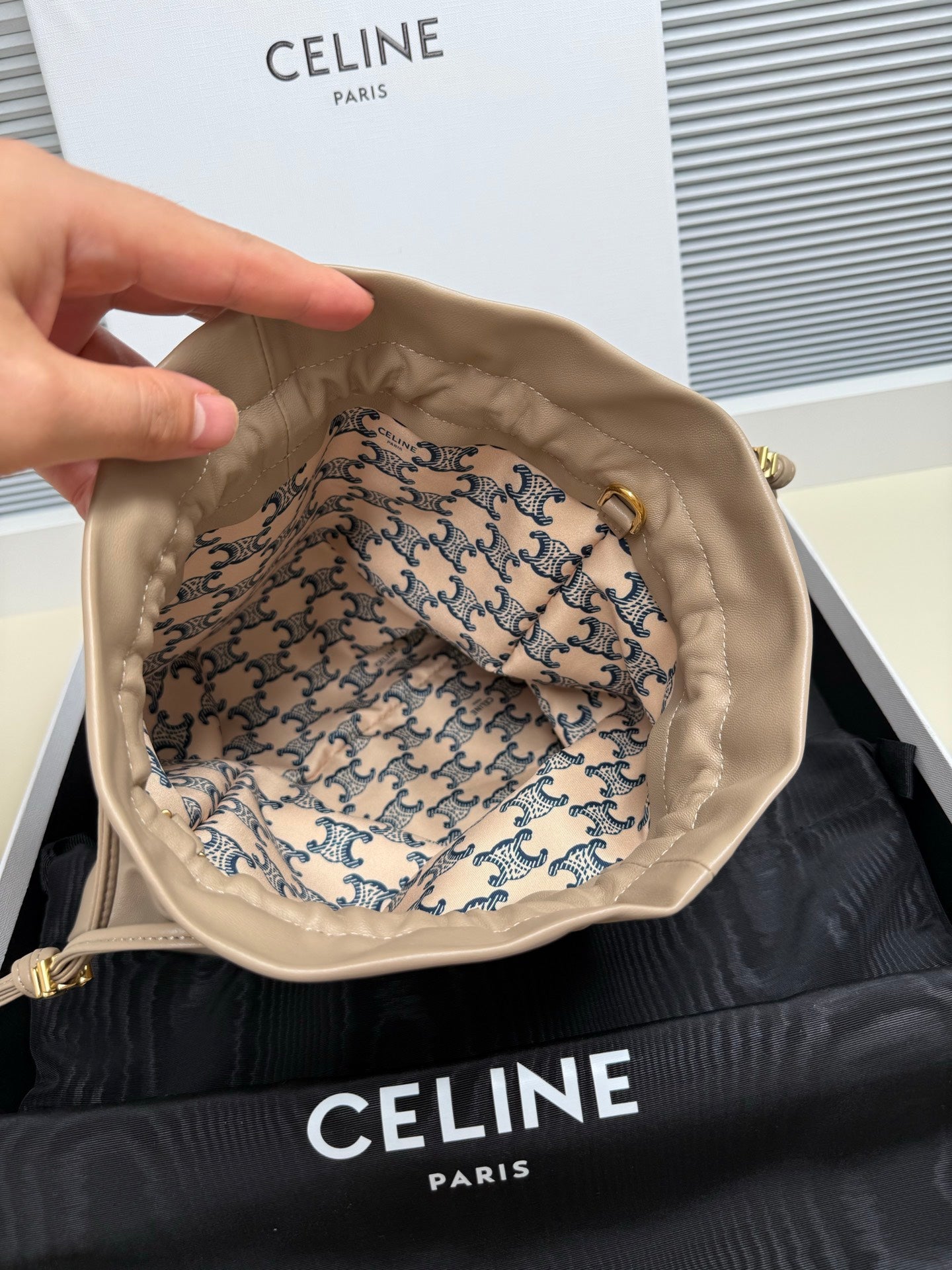 Beige leather drawstring pouch open inside view with patterned lining and braided ties