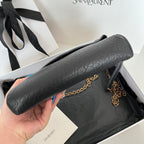 Black textured leather YSL shoulder bag with chain strap, held in hand