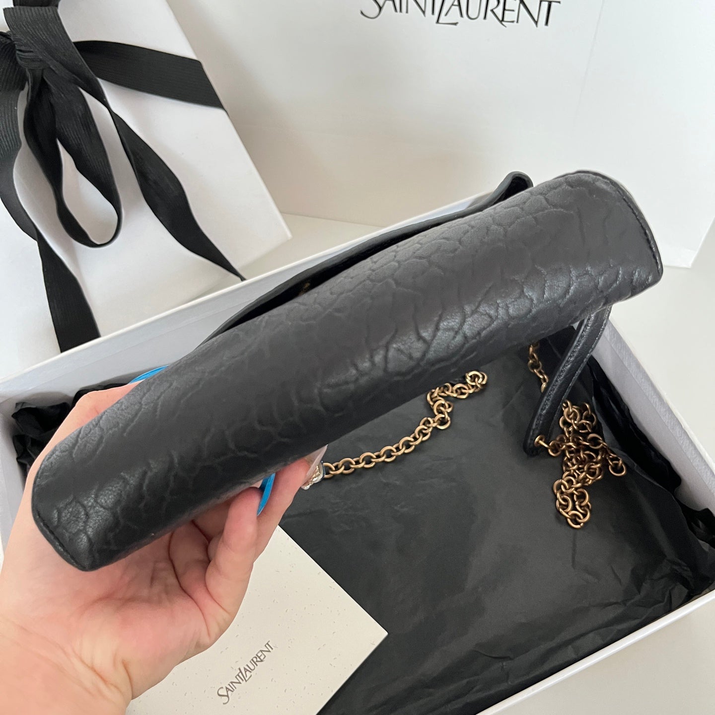 Black textured leather YSL shoulder bag with chain strap, held in hand