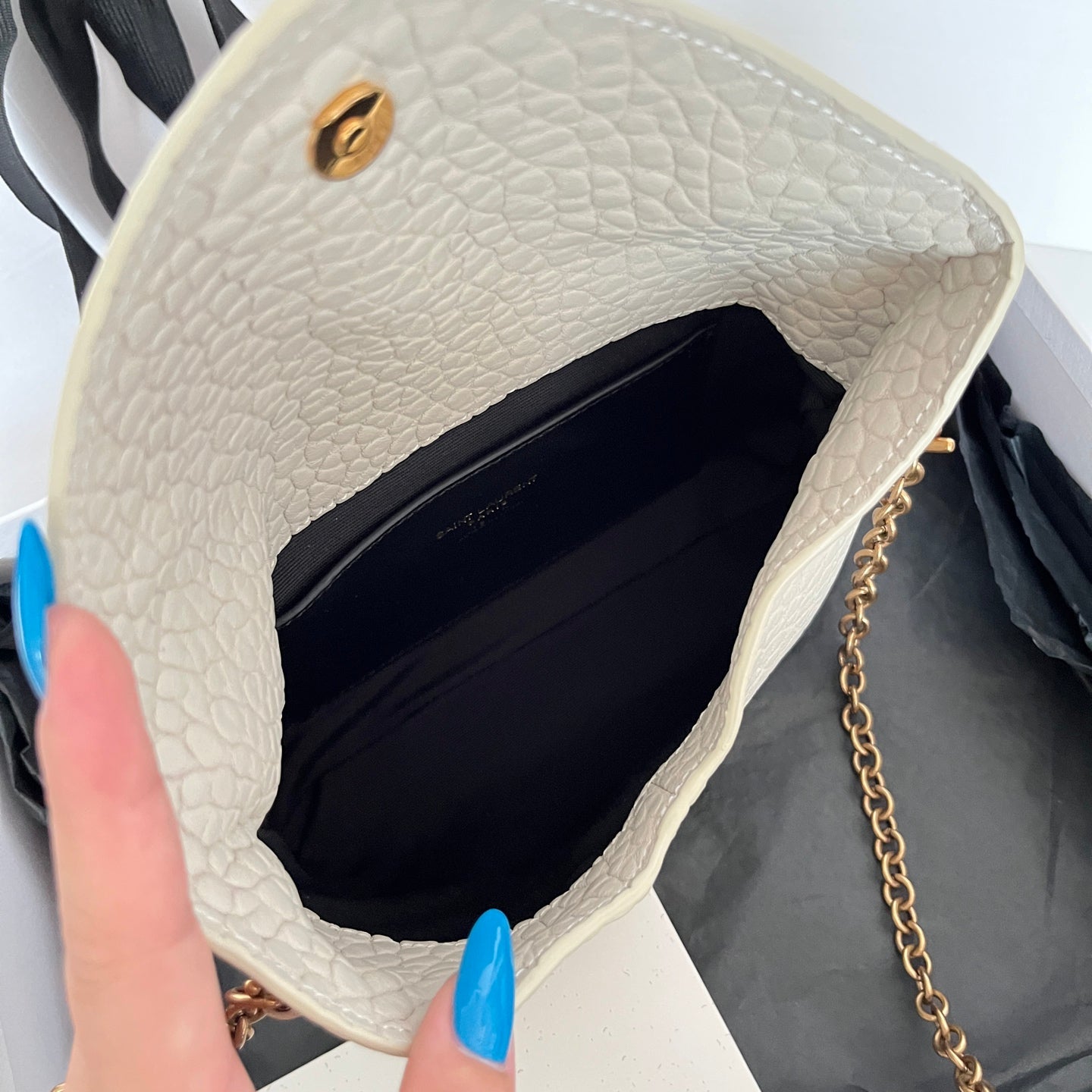 Light off-white textured shoulder bag interior with dark lining and chain strap in frame