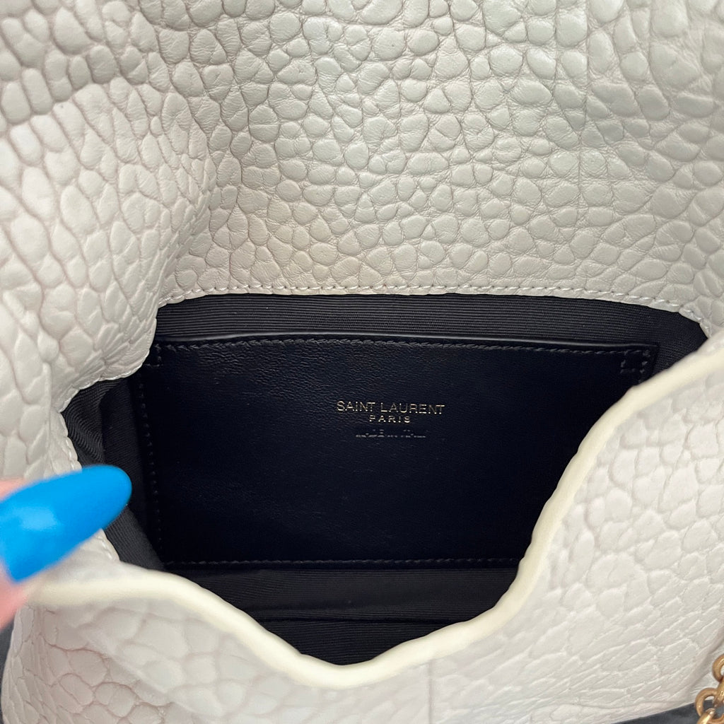 Close-up of light off-white textured flap interior lining with small Saint Laurent label