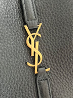 YSL bag detail, gold monogram charm on black pebbled leather