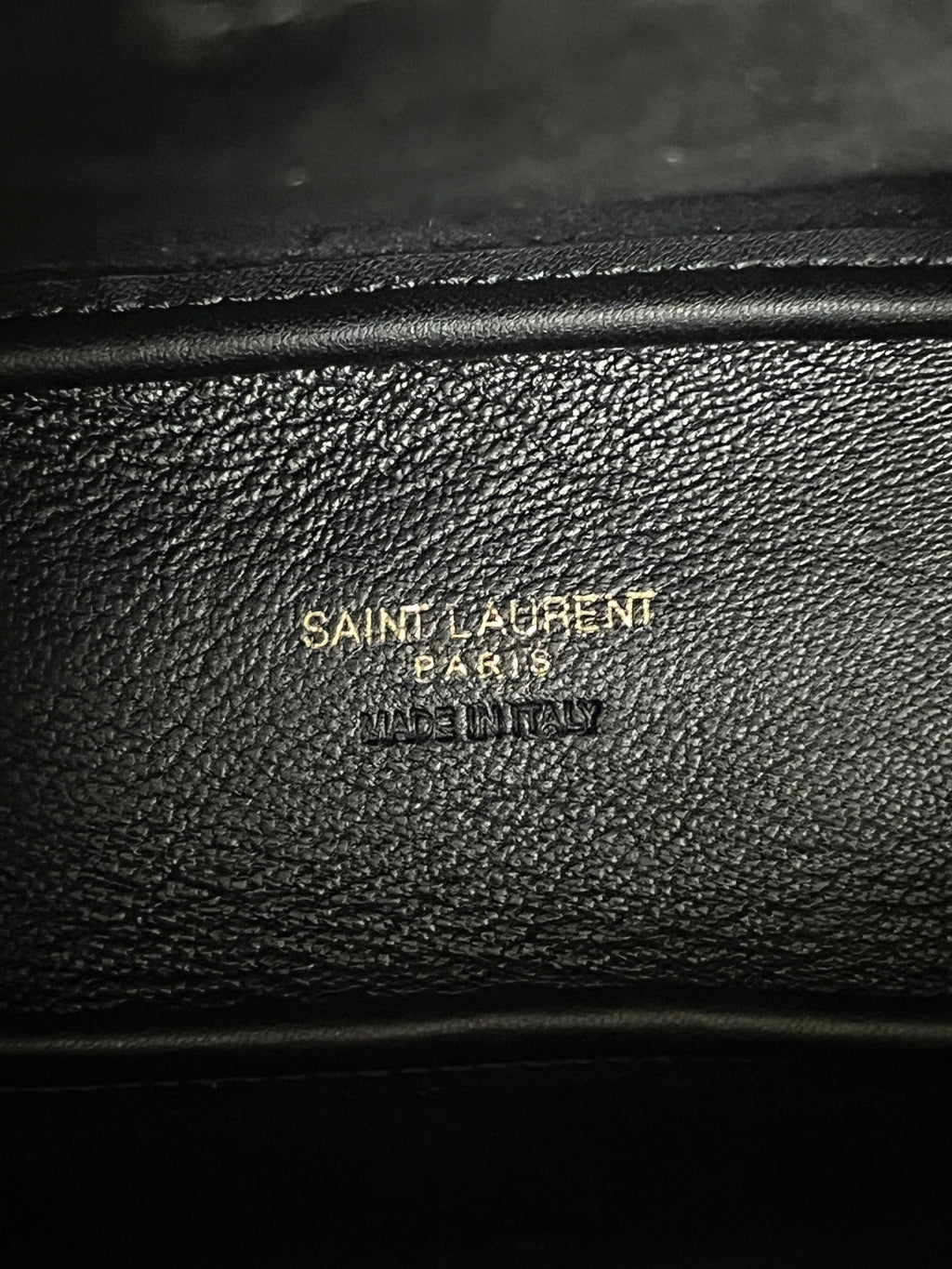 YSL bag close-up, black pebbled leather with embossed brand text