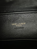 YSL bag close-up, black pebbled leather with embossed brand text