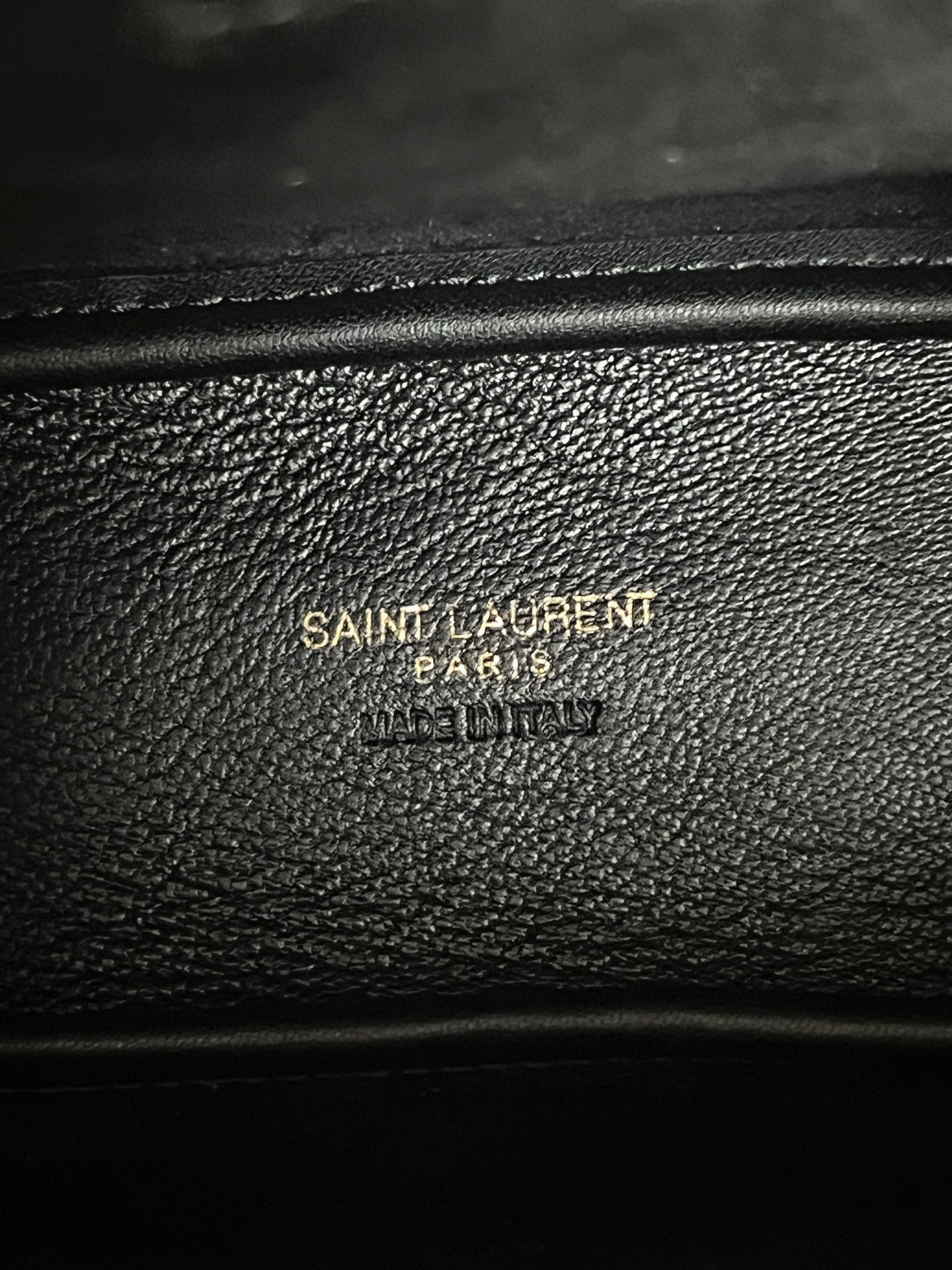 YSL bag close-up, black pebbled leather with embossed brand text