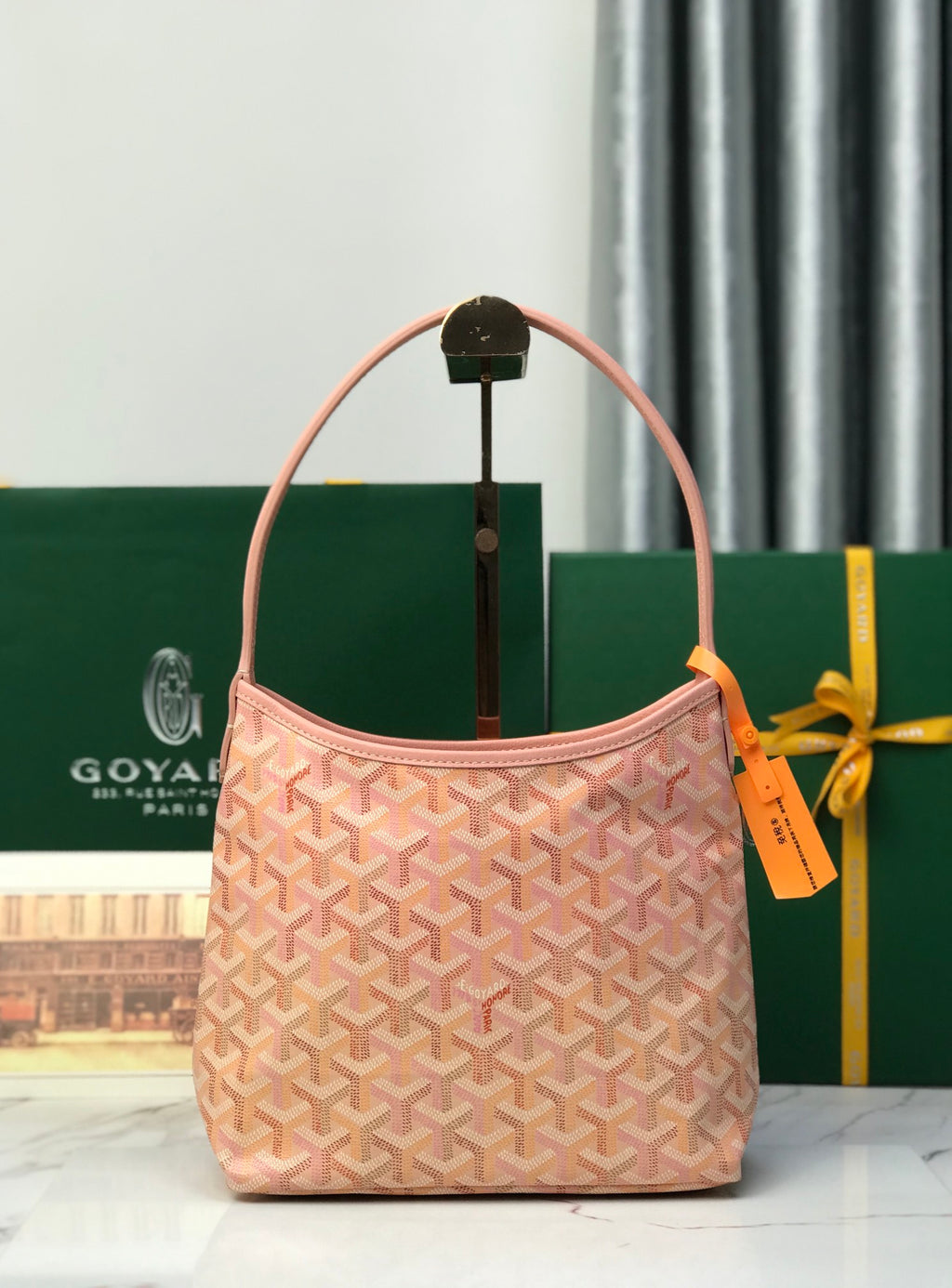 Pink Goyard-style canvas tote bag with curved handles and hanging tag