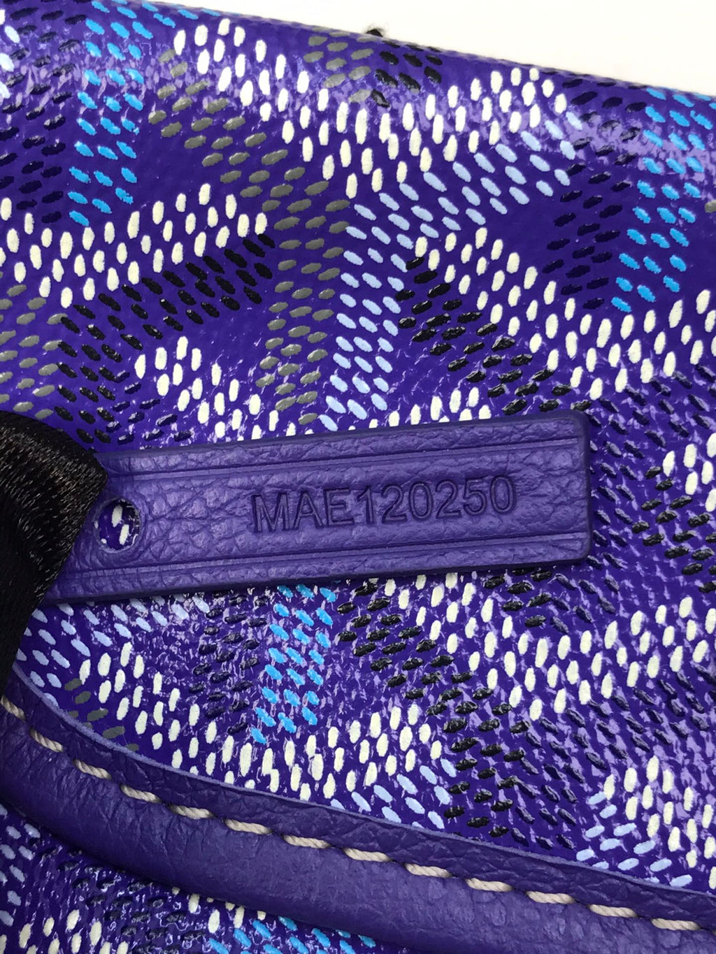 Purple leather tab with embossed code on Goyard patterned bag flap