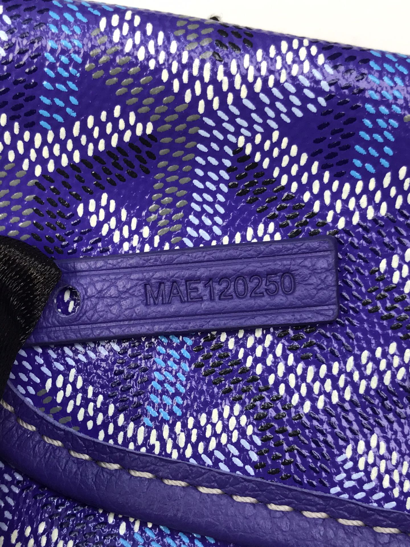Purple leather tab with embossed code on Goyard patterned bag flap
