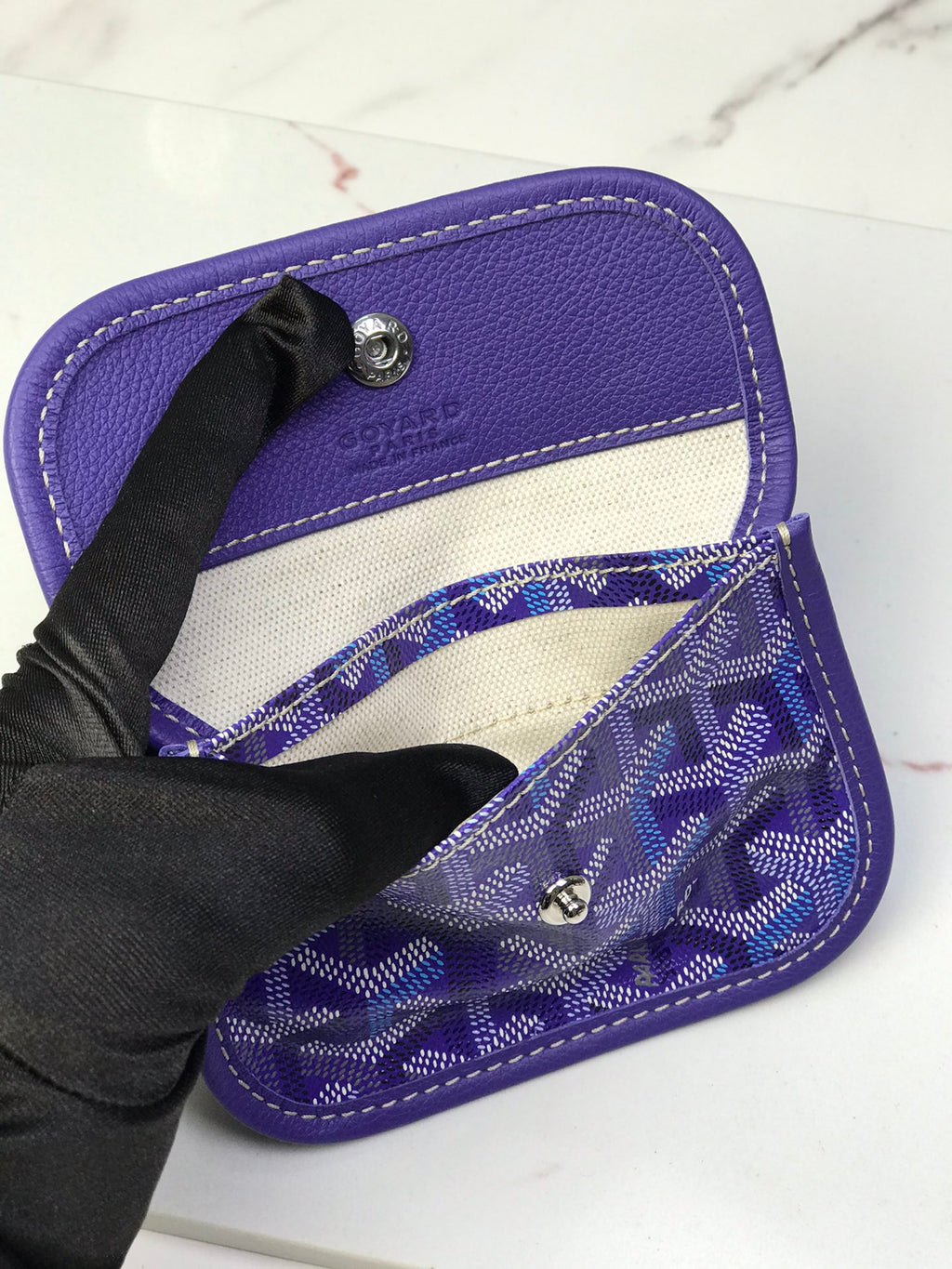 Goyard bag interior with purple lining, open top, and snap hardware