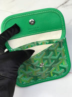 Green Goyard insert wallet with snap closure and monogram fabric panel.
