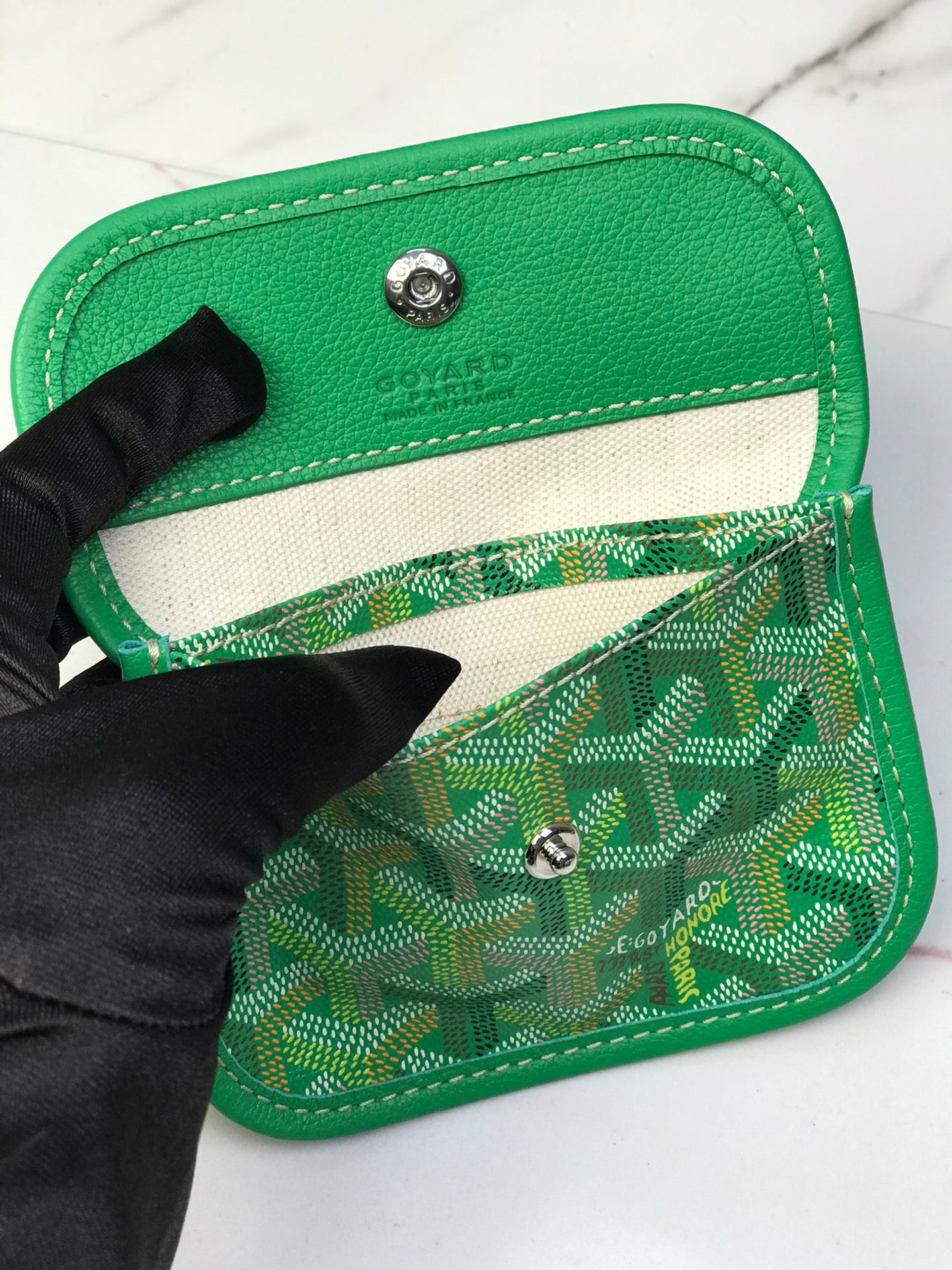 Green Goyard insert wallet with snap closure and monogram fabric panel.