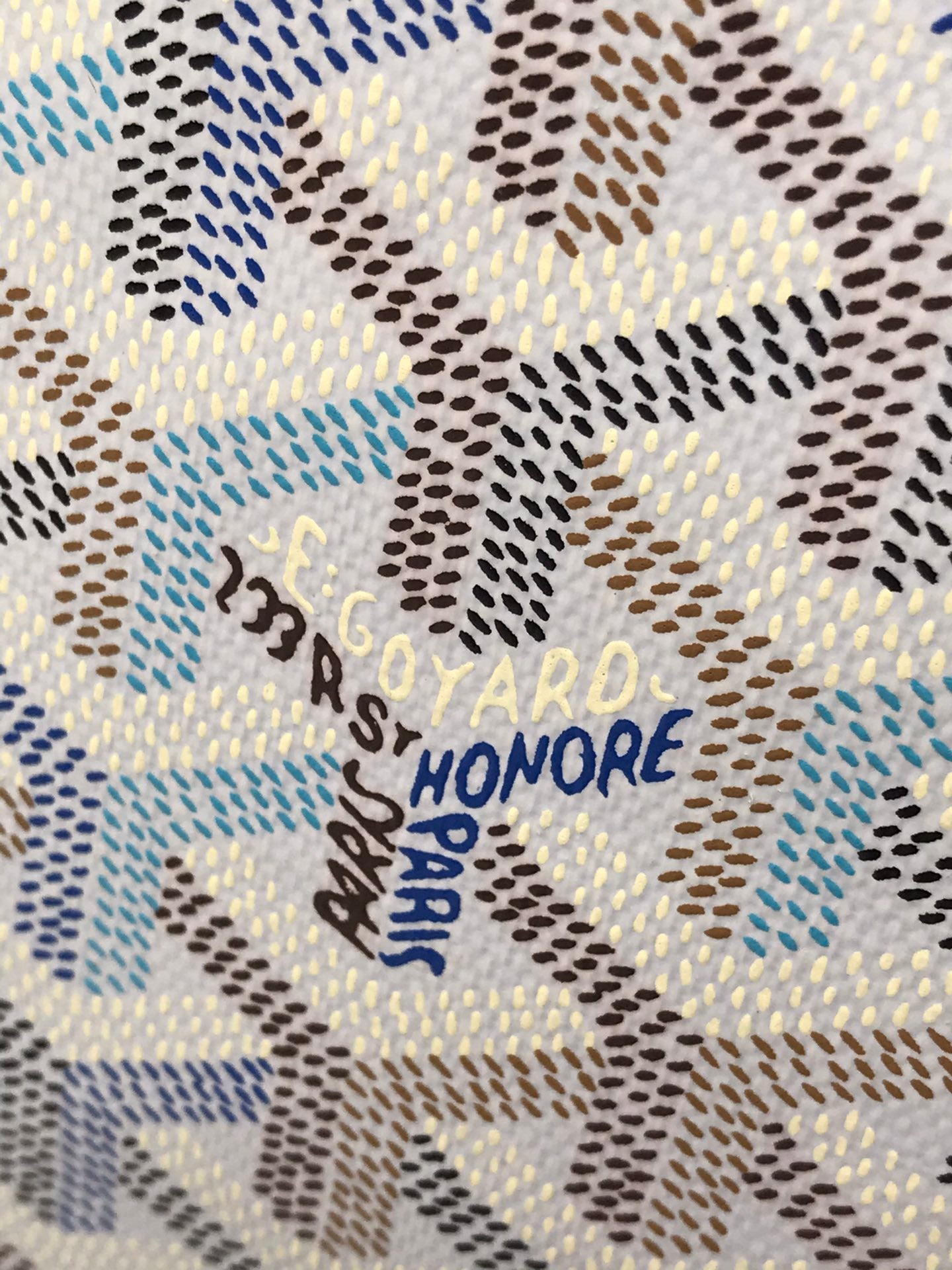 Goyardine canvas close-up with blue and gold 'PARIS HONORE' lettering