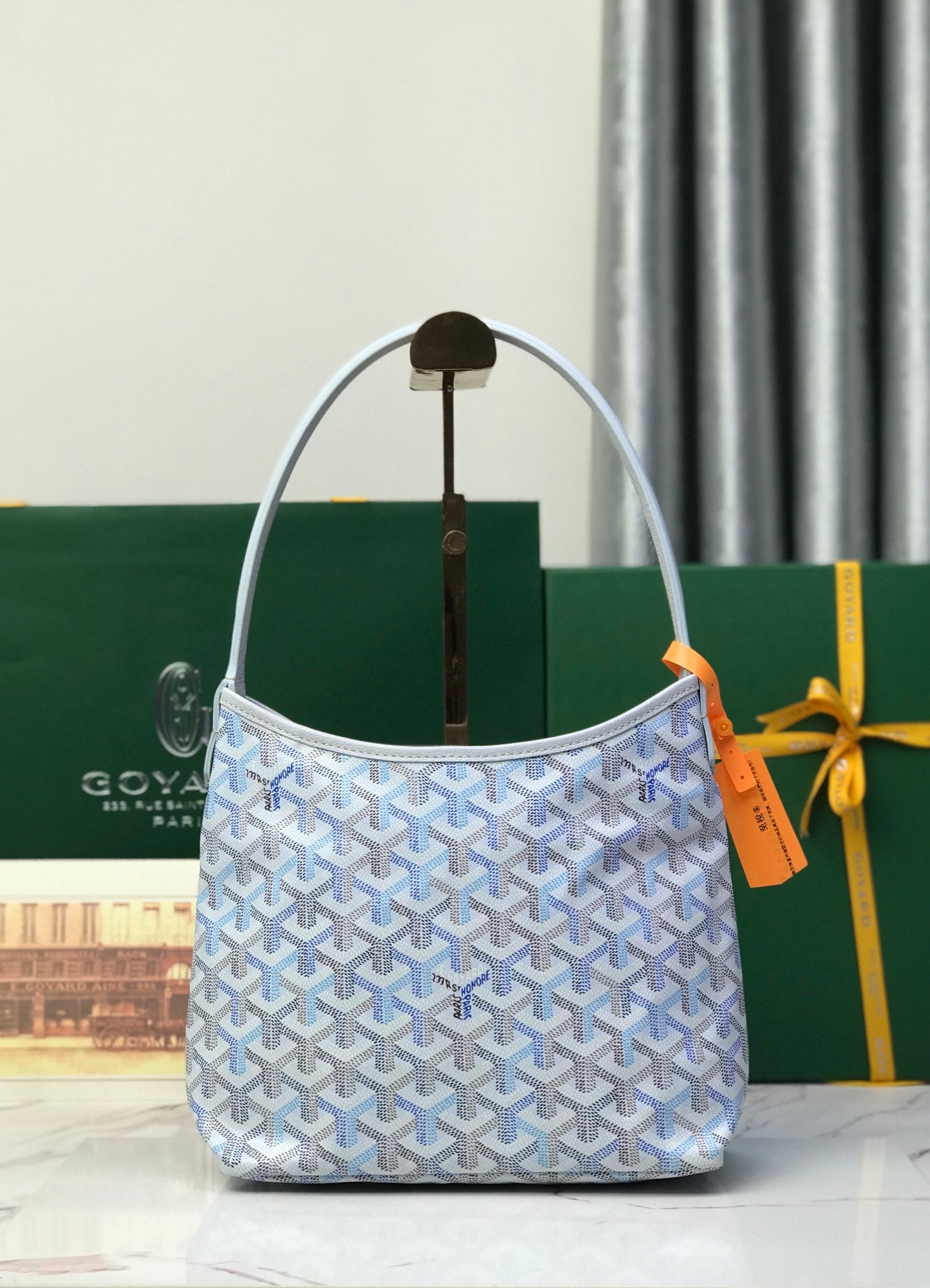 Goyard small bucket bag in light blue with curved top handles and orange tag