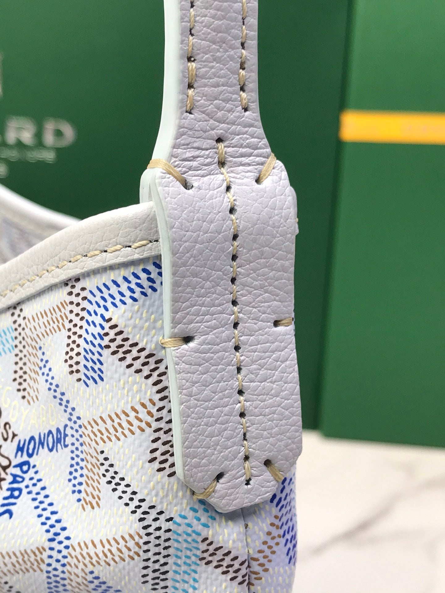 Goyard bag handle close-up with textured light leather and gold stitching