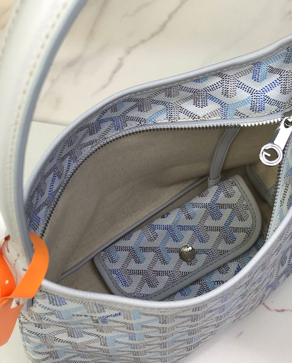 Goyard bag interior with zip pocket, circular logo, and light blue Goyardine lining