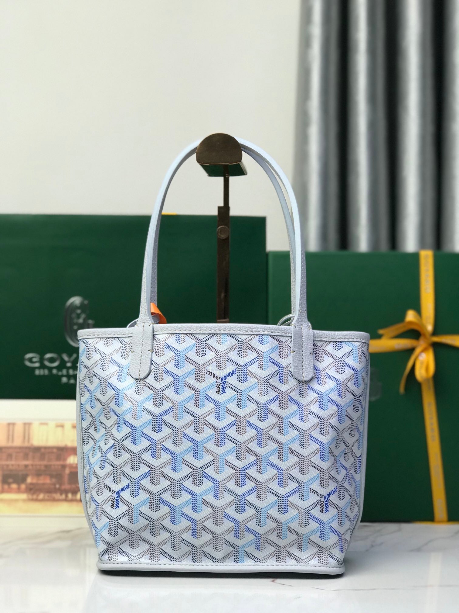 Goyard monogram tote bag with top handles, open top, and orange pull tag