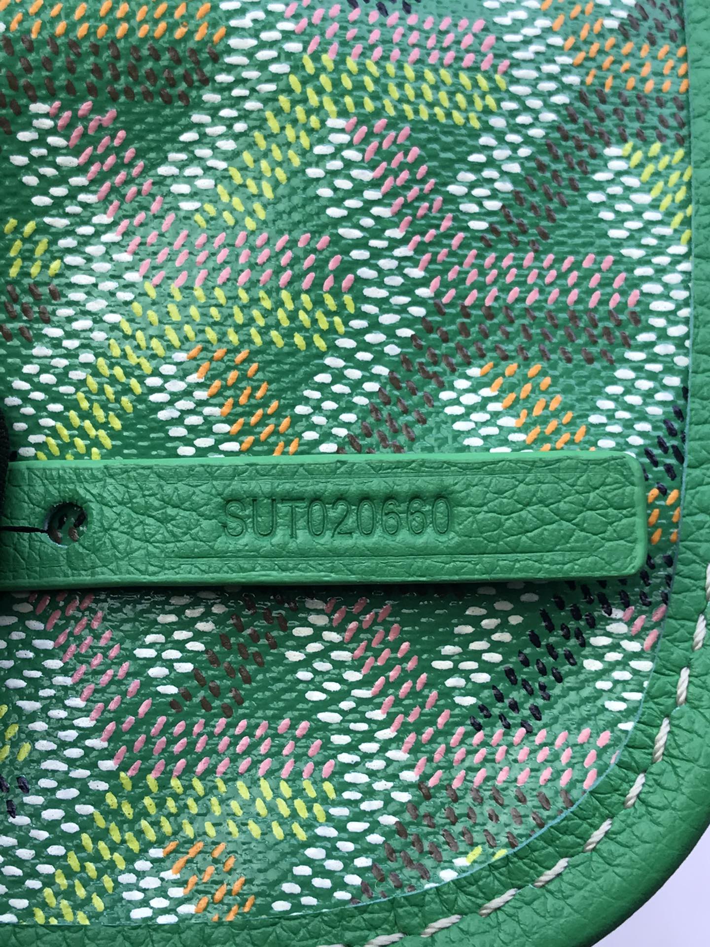 Green leather trim with stamped logo on patterned canvas
