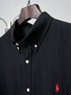 Black button-up shirt collar with white buttons and small red polo logo