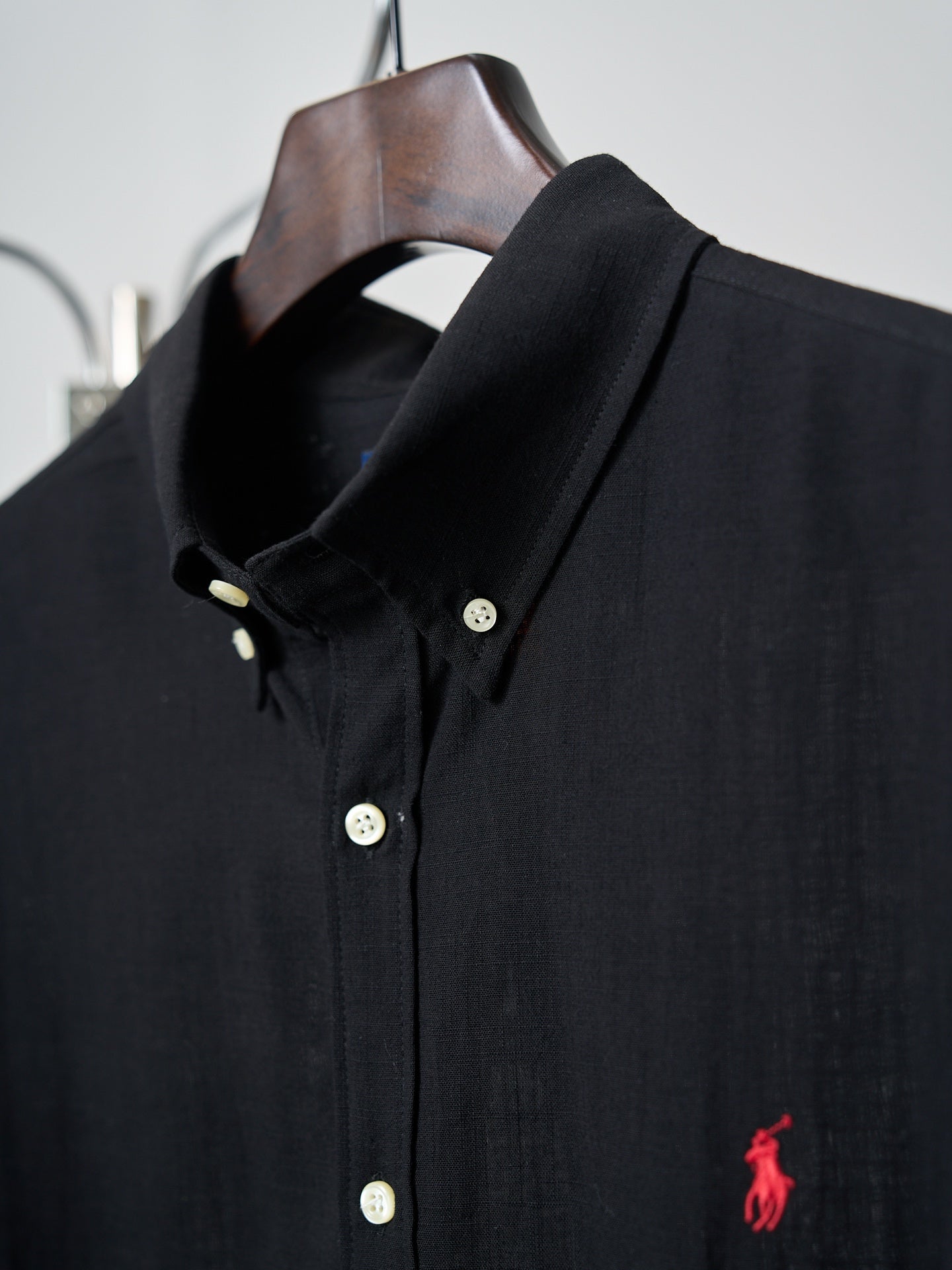 Black button-up shirt collar with white buttons and small red polo logo
