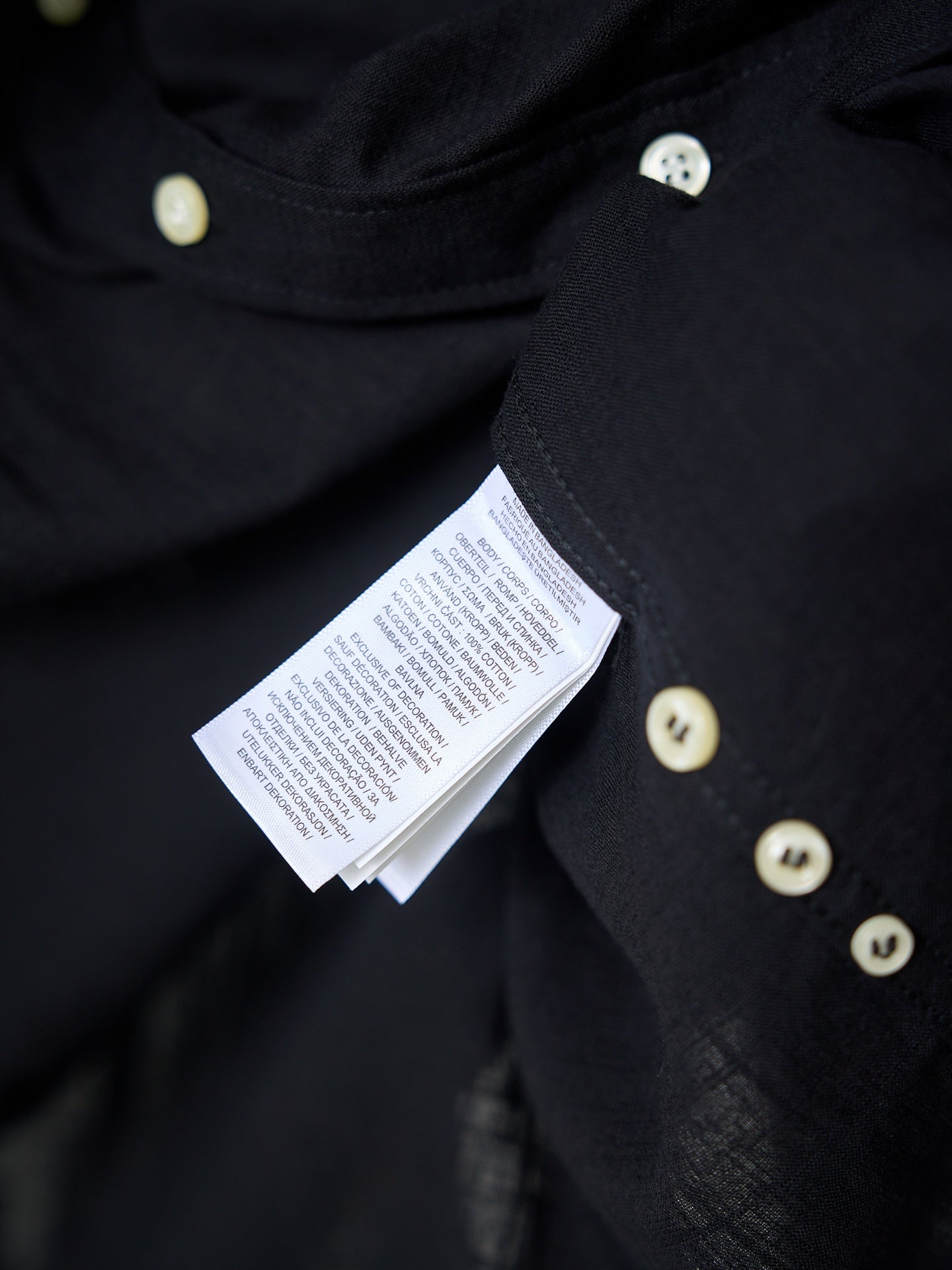 Dark button-front garment with attached care label