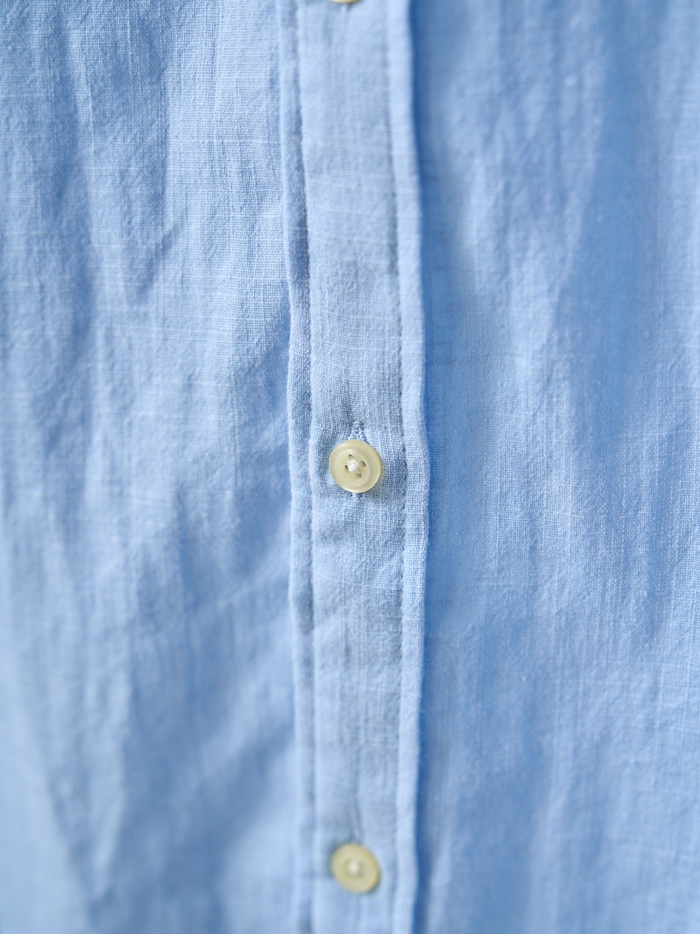 Light blue buttoned shirt placket with round yellow buttons