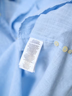 Light blue shirt with care label and yellow buttons on the placket