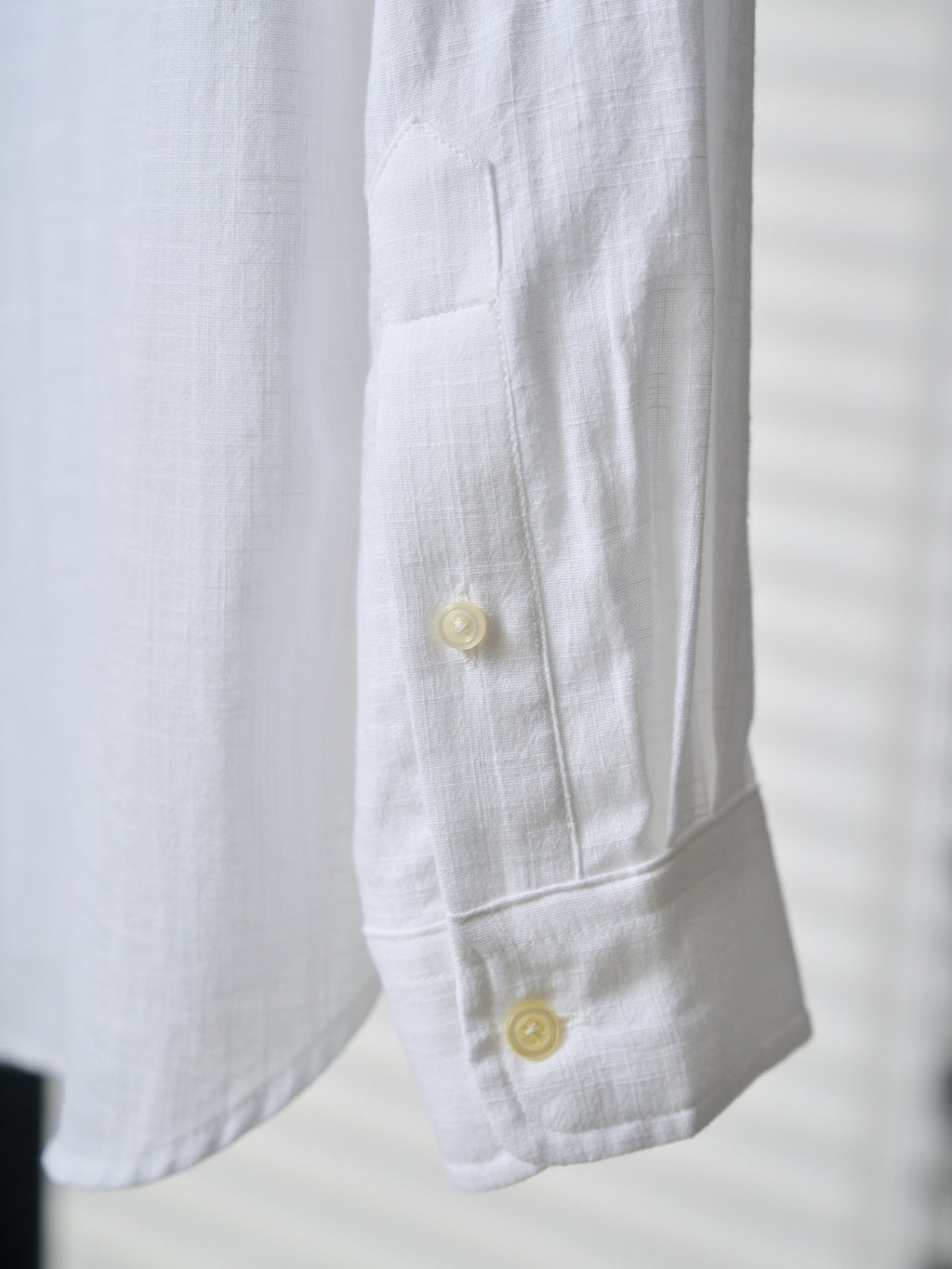 White shirt cuff with two yellow buttons and visible seam stitching