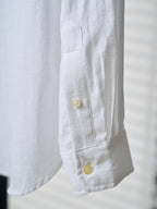 White shirt cuff with two yellow buttons and visible seam stitching