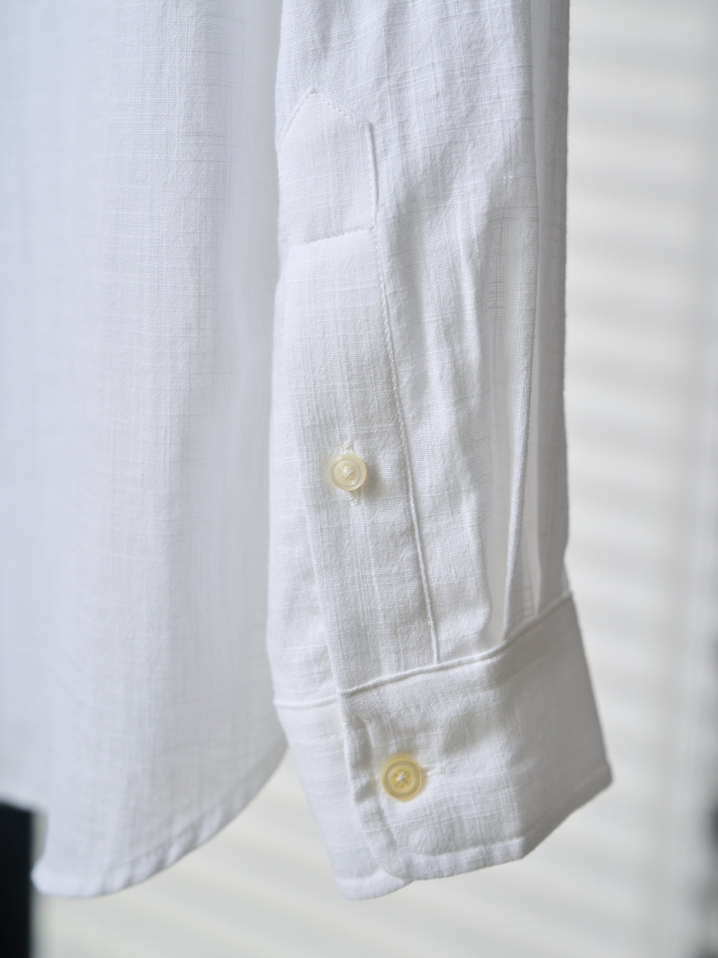 White shirt cuff with two yellow buttons and visible seam stitching