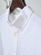 White button-up shirt collar with yellow buttons and small gold logo detail