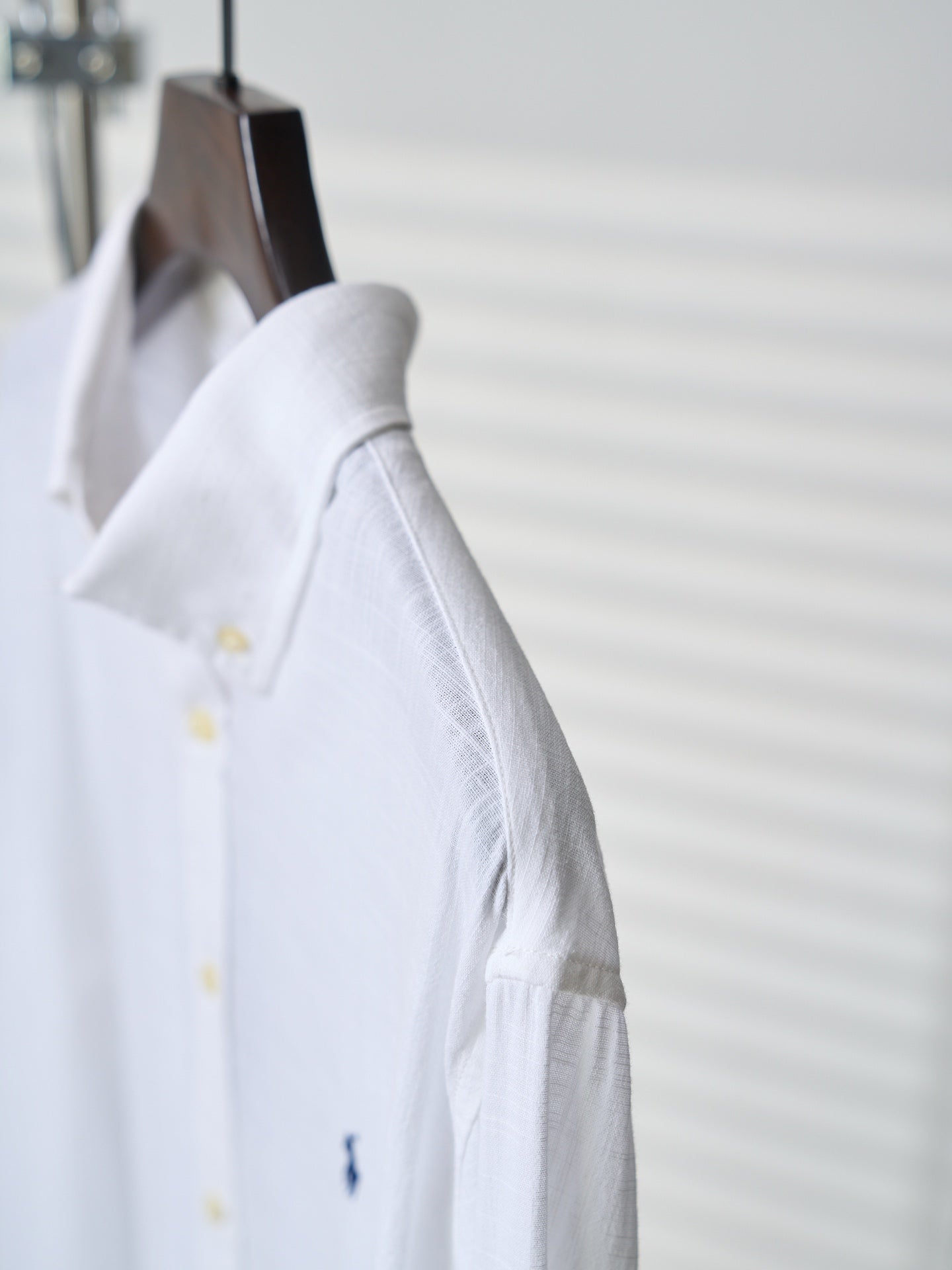 White button-up shirt sleeve with gathered cuff and small yellow button