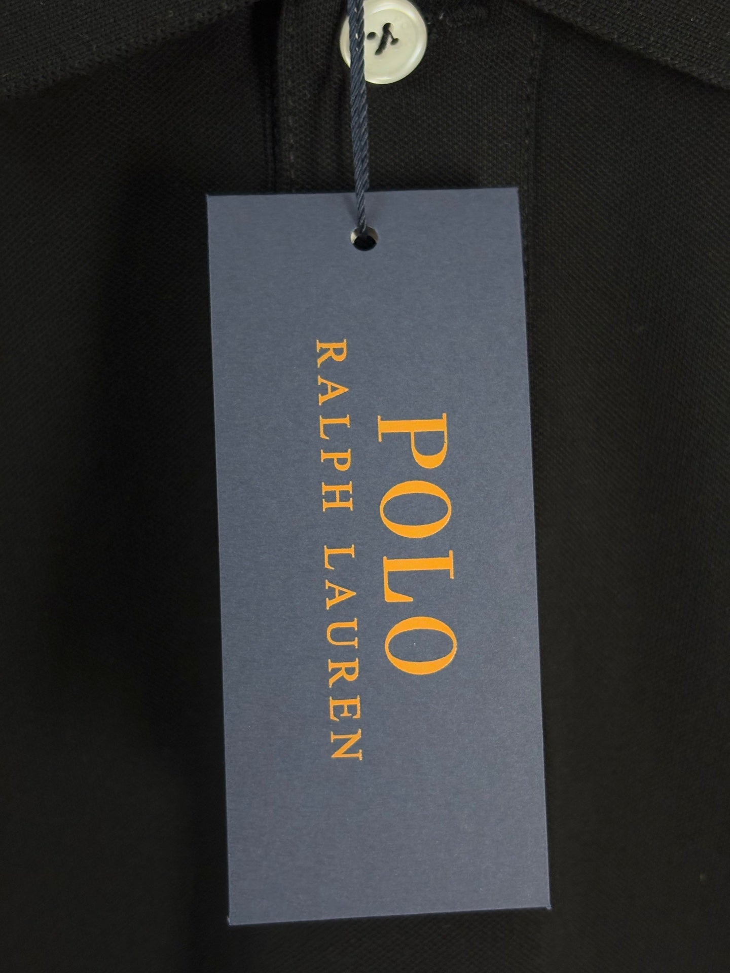 Black polo shirt with POLO Ralph Lauren retail tag hanging from collar