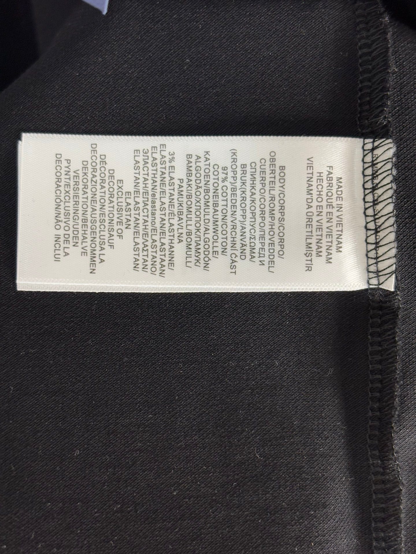 Black polo shirt interior care label with printed product instructions