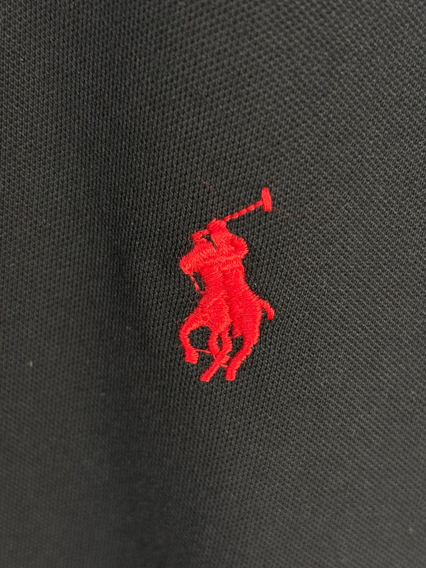 Red Polo pony logo on black textured polo fabric