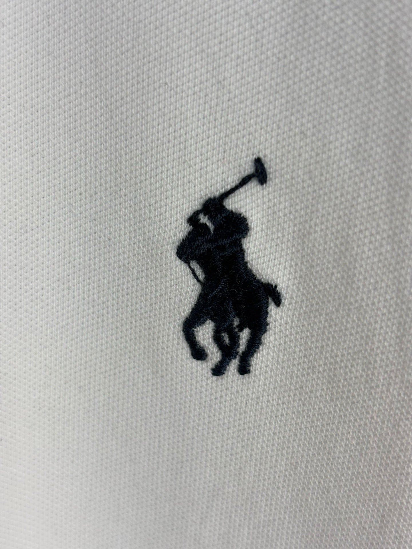White polo knit with embroidered navy horse player logo
