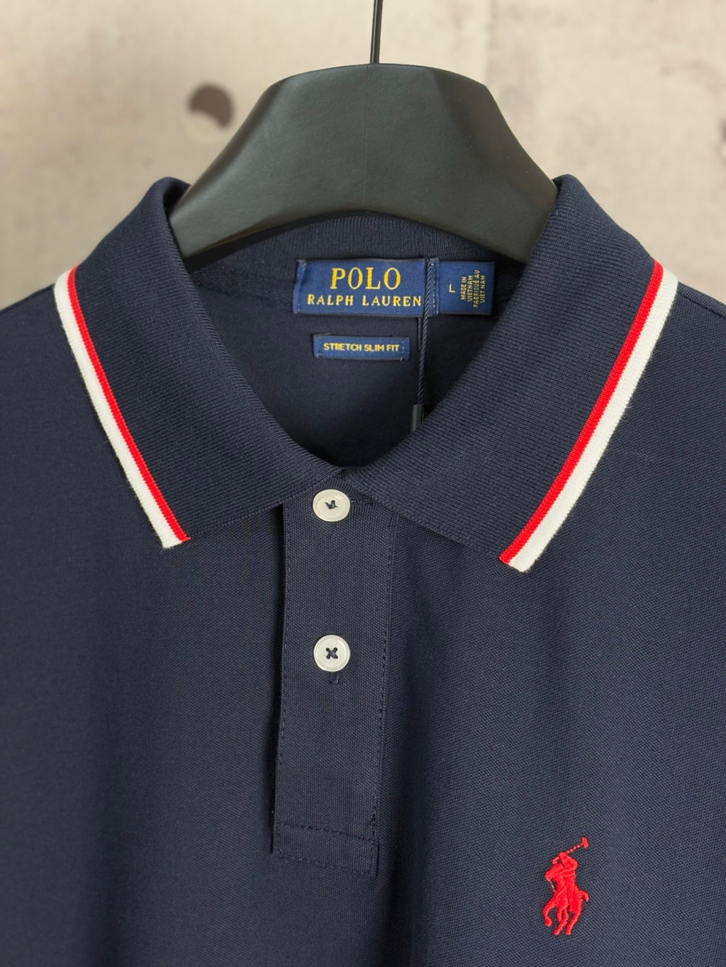 Navy polo shirt collar with red-and-white striped trim and button placket detail