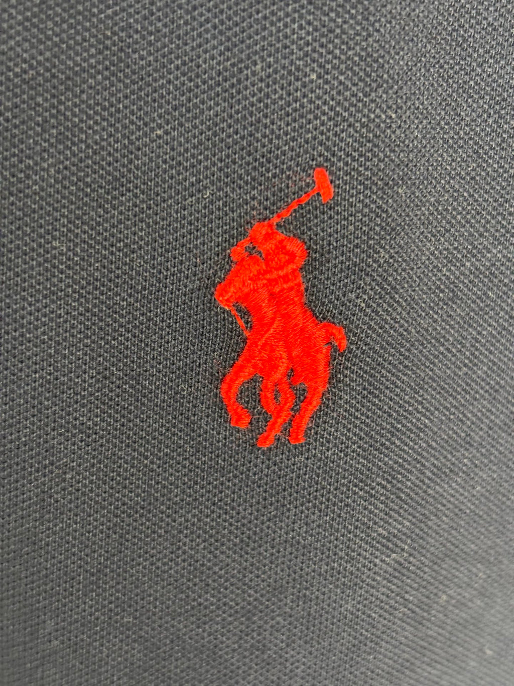 Red Polo player logo on navy polo shirt fabric