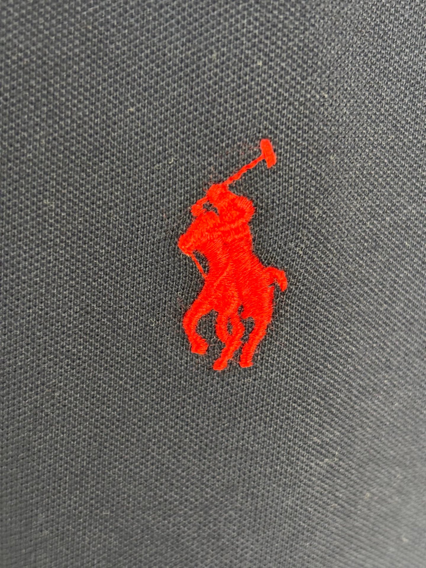 Red Polo player logo on navy polo shirt fabric