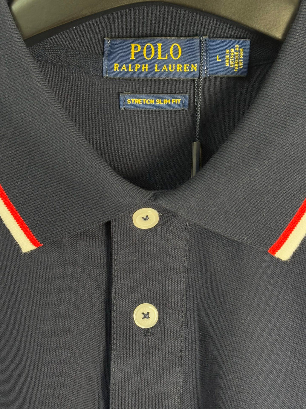 Navy polo shirt neckline with two-button placket and red-and-white collar stripes
