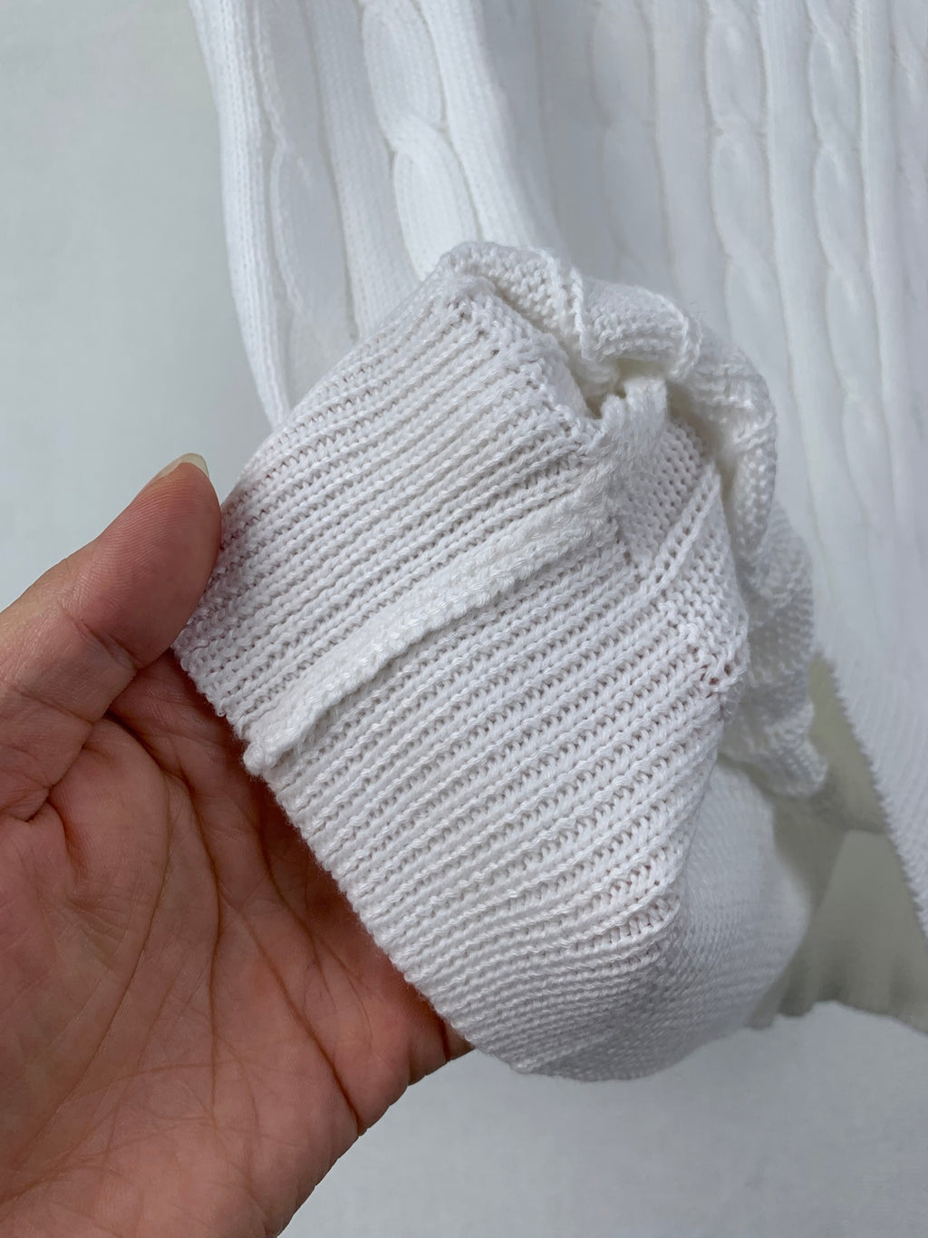 Folded white knit cuff piece with ribbed texture and drawstring end