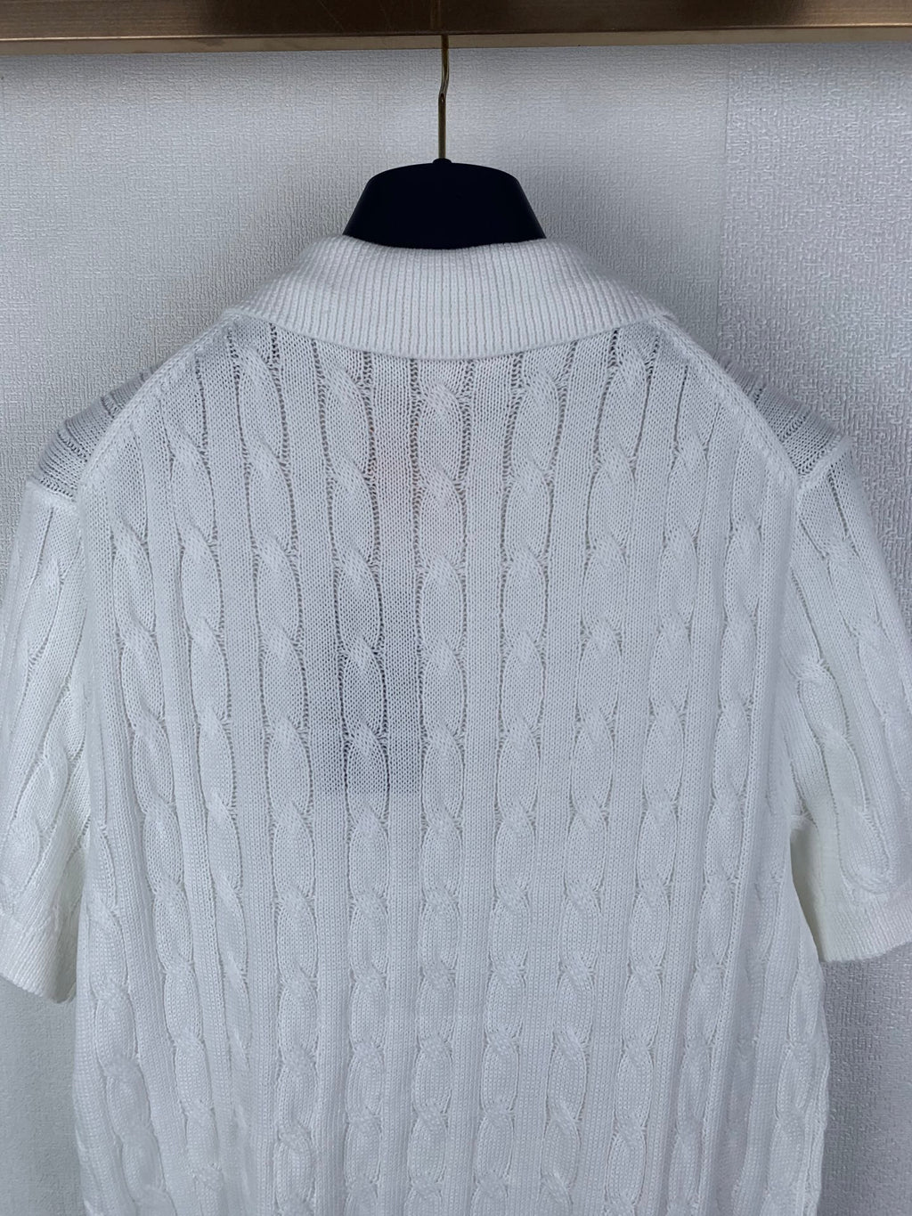 White cable-knit polo shirt back view with ribbed collar and textured knit