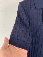 Dark navy cable-knit polo shoulder and sleeve with ribbed knit texture