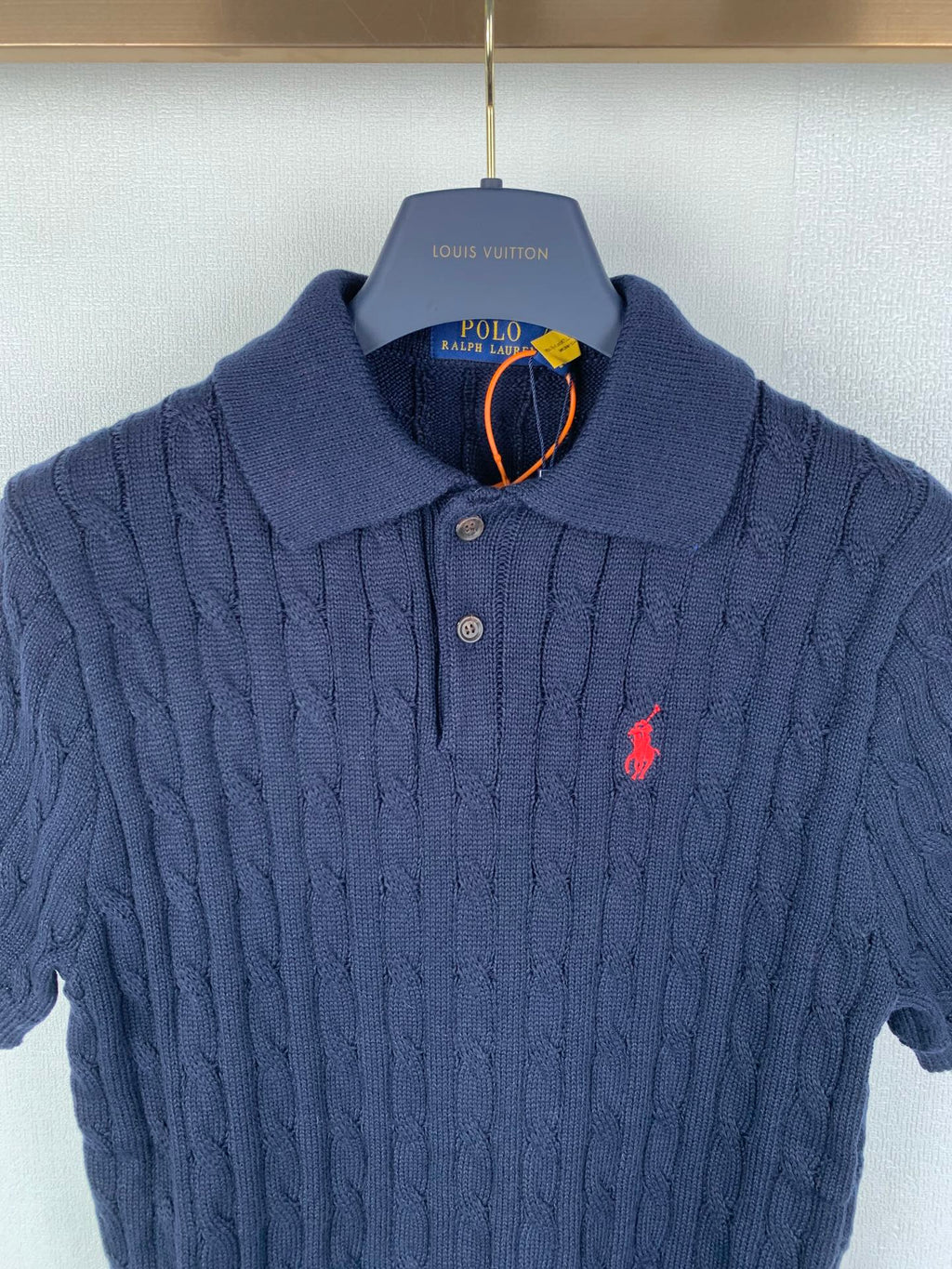 Dark navy cable-knit polo shirt with button placket, red logo, ribbed collar